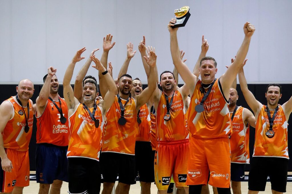 Equipo de baloncesto celebrando un título con la equipación naranja fabricada por Kauri